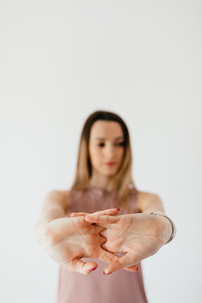 A young woman stretching her hands forward with focus and calmness in an indoor setting.